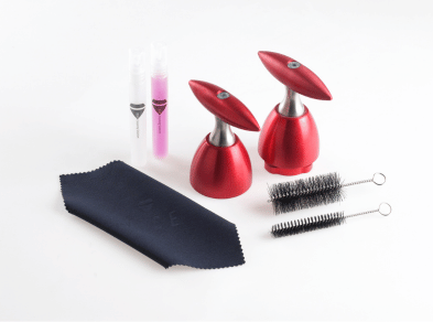 A handheld tablet press with various cleaning accessories.