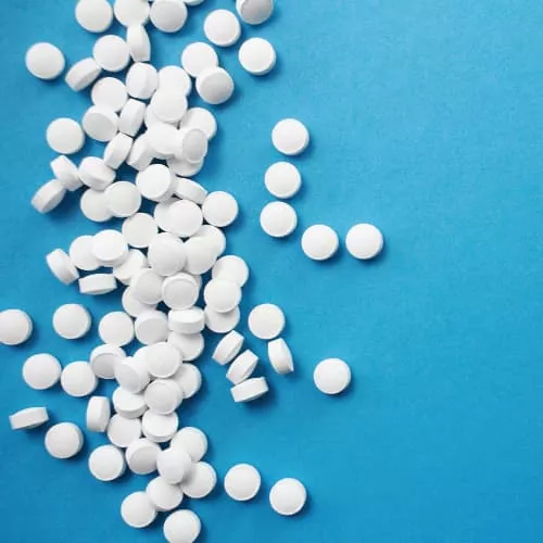 Perfectly formed white tablets against a blue background.