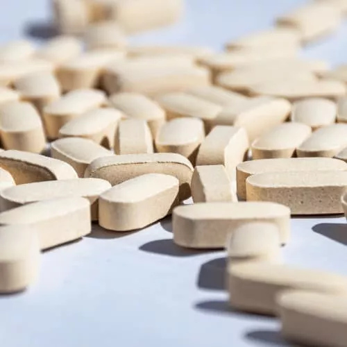 A close up of a pile of tan colored caplet tablets 